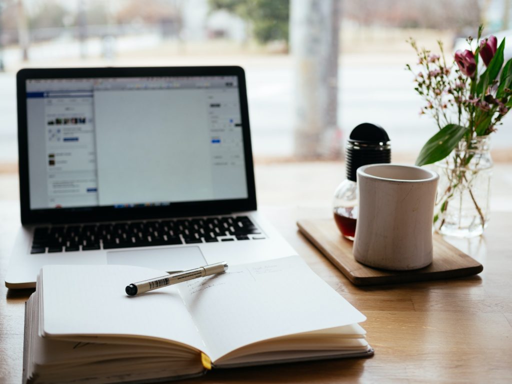 A computer and a notebook on a writing desk.