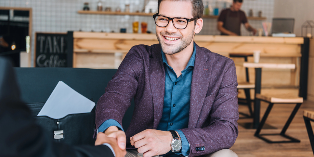 A young man shakes hands at a business meeting at a coffee shop