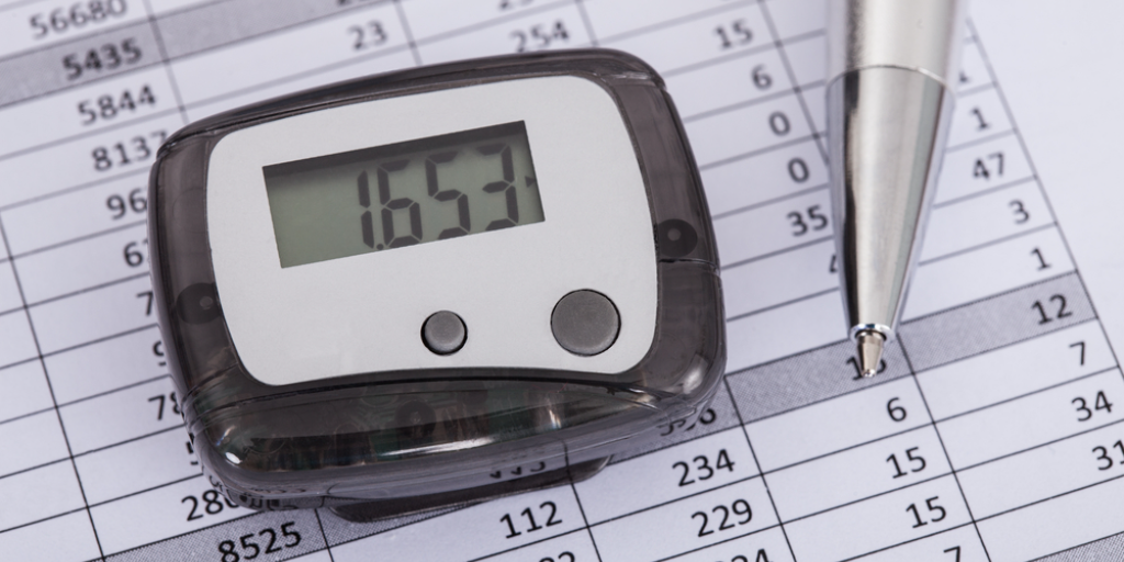 A digital pedometer on top of a chart of numbers.