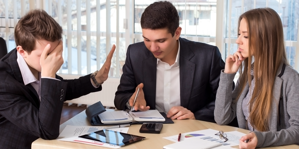 A man in a meeting is distancing himself from the others at the table