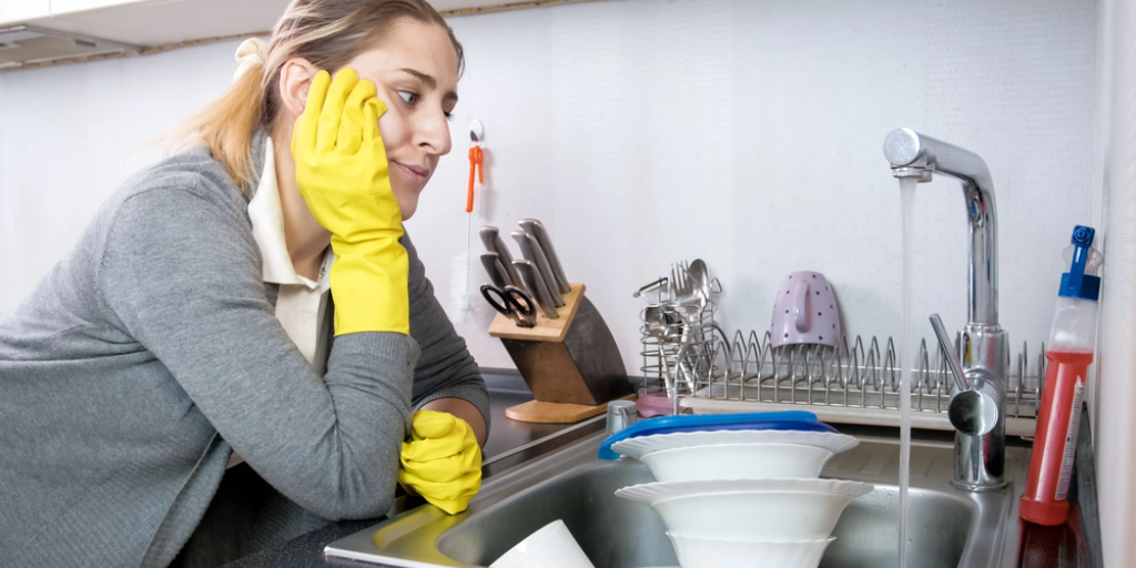 A woman at a sink full of dishes