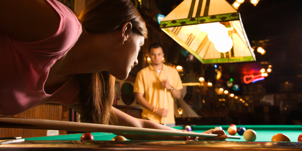 A young woman playing billiards in a pool hall