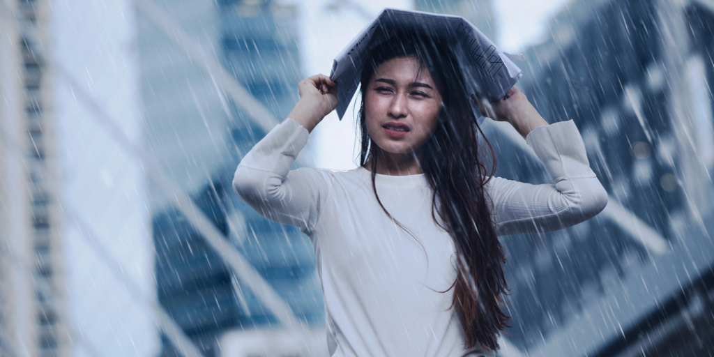 A girl uses a newspaper to protect herself from the rain. An umbrella would be better