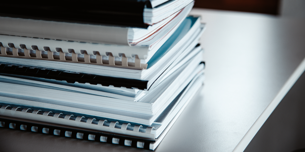 Stack of reports lies on a desk ready for review and editing