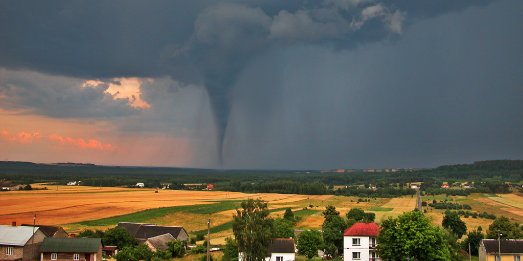 View of the serene countryside and stormy sky with a tornado in the background.
