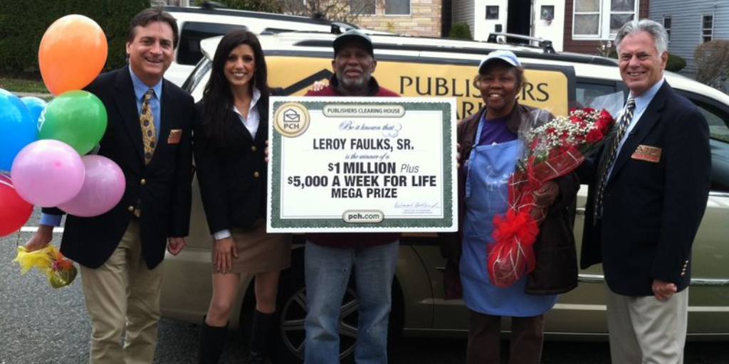 A photo of a prize winner holding an over-sized check that promised $5,000 for life